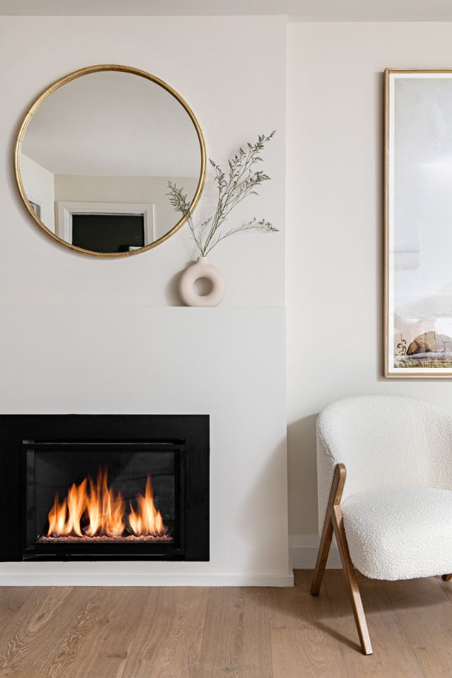 fireplace in bedroom with gold mirror and hardwood floor